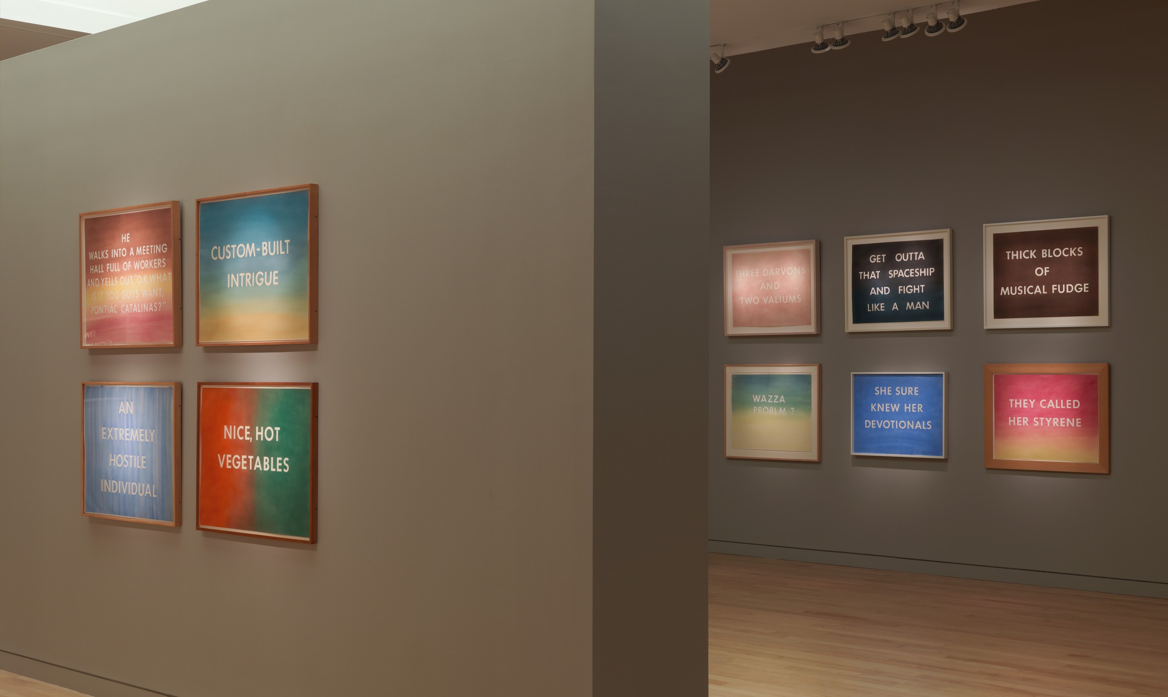 A collection of Ed Ruscha paintings hanging on a gallery wall